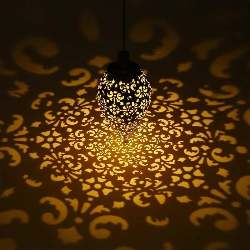Lanterne solaire goutte d'eau en métal bronze antique projetant des ombres florales
