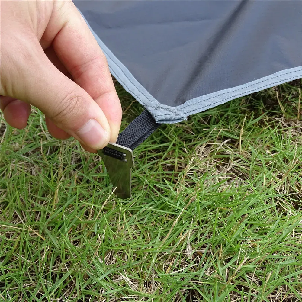 Détail des coins du tapis de camping avec piquets en aluminium