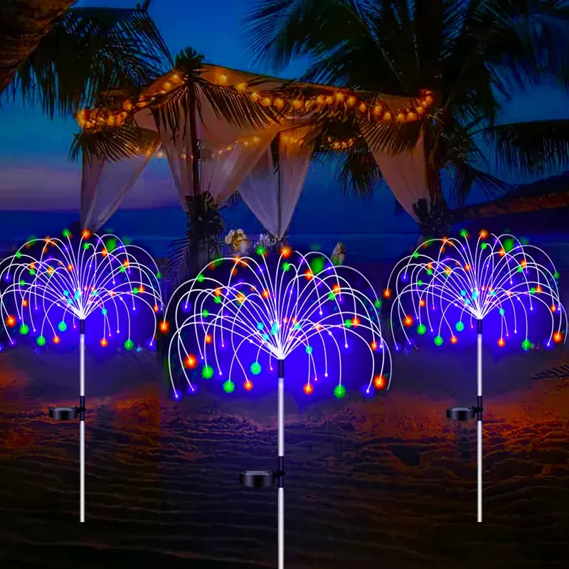 Lampe solaire de jardin en forme de feu d'artifice illuminant une pelouse la nuit